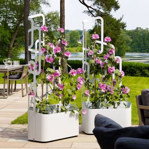 Image of pair of Flora Paro white planters with trellis, shown on terrace with lawn, trees and lake in the background