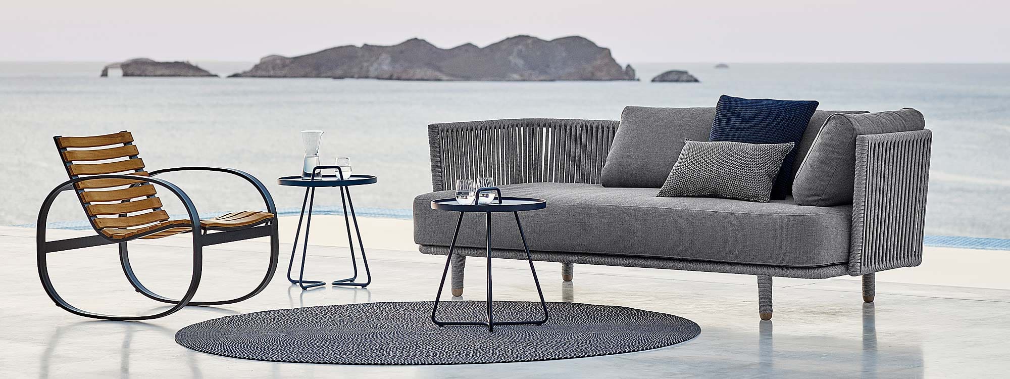 Image of terrace at dusk with Moments 2 seat outdoor sofa and On The Move side tables by Cane-line