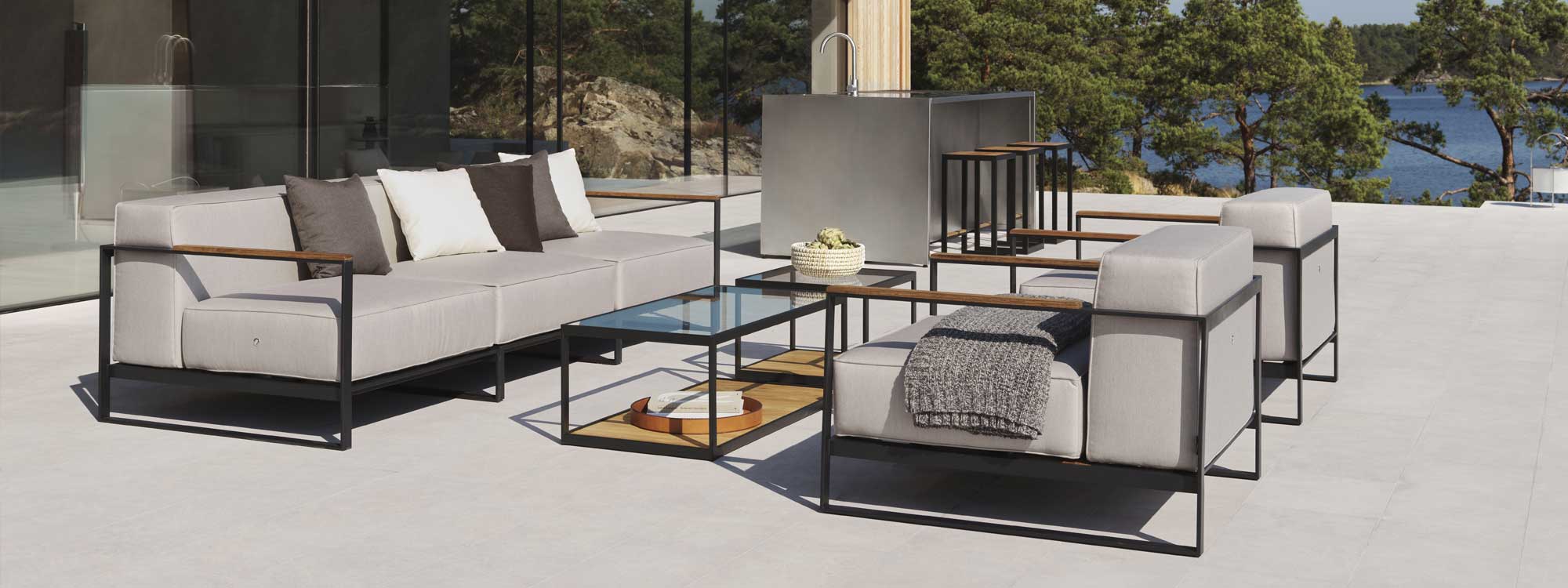 Image of Moore large garden sofa and lounge chairs on minimalist terrace in Swedish countryside, with lake and woodland in the background