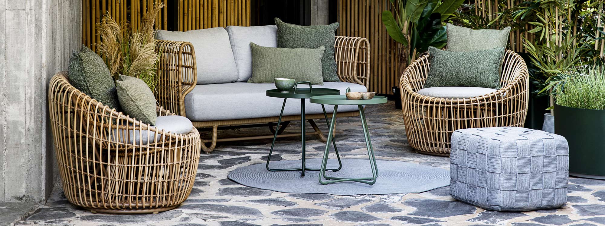 Image of Cane-line Nest sofa and lounge chairs in natural Cane-line weave with On The Move garden tray tables in the centre