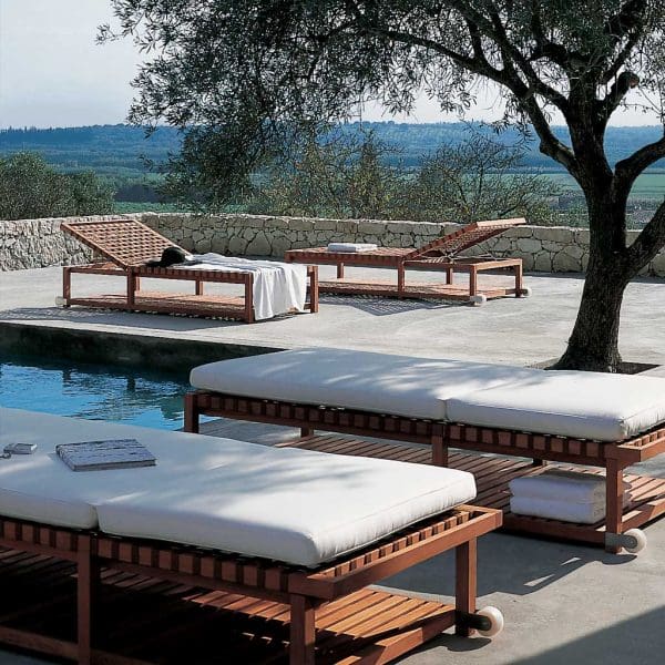 Image of RODA Network teak sunbeds beneath shade of tree, next to swimming pool with Italian countryside in background