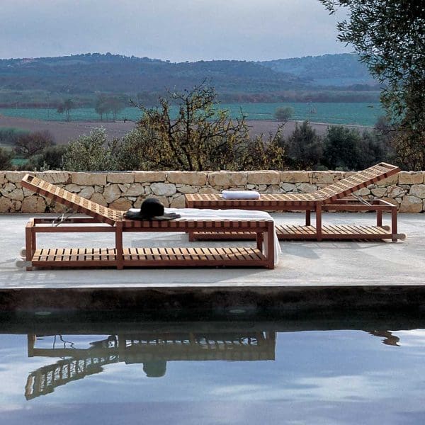 Image of pair of RODA Network modern teak sunbeds with brown webbing seat & backrest next to poolside with Italian countryside in background