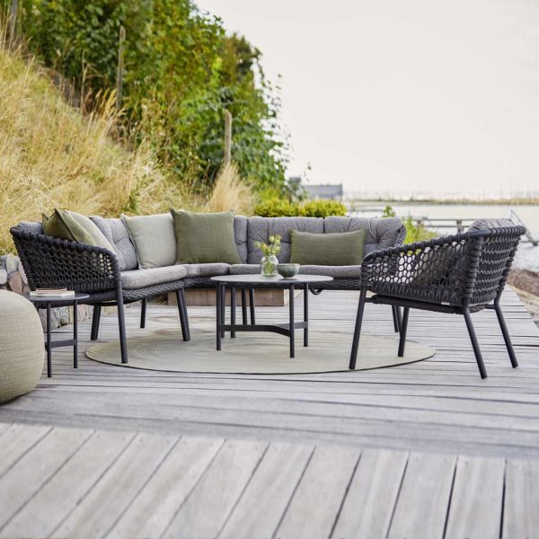 Image of Ocean modular garden sofa and Twist low table by Caneline, shown on wooden decking