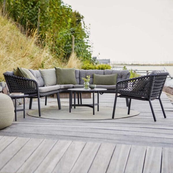 Image of Ocean modular garden sofa and Twist low table by Caneline, shown on wooden decking