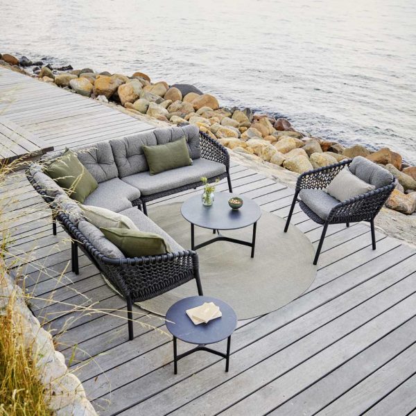 Image of Ocean L-shaped garden sofa and lounge chairs on decking beside grey water by Caneline
