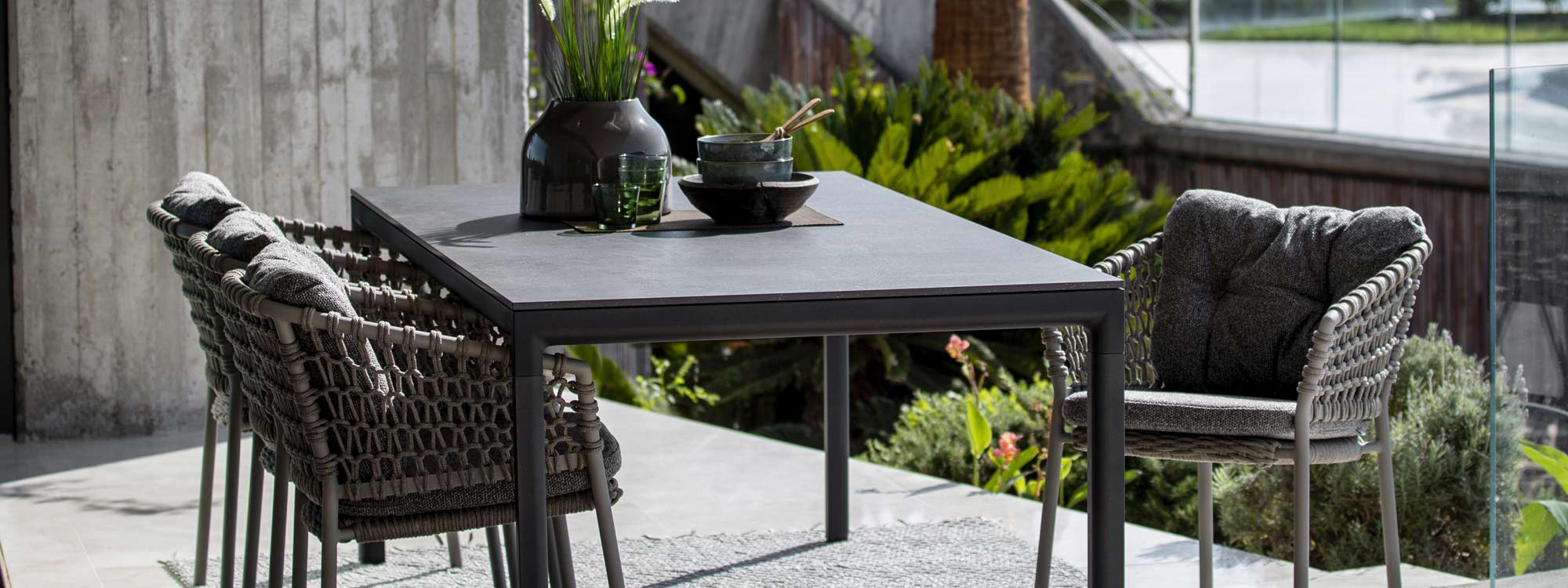 Image of dark grey Ocean garden chairs and lava grey Drop dining table with black fossil ceramic top by Cane-line