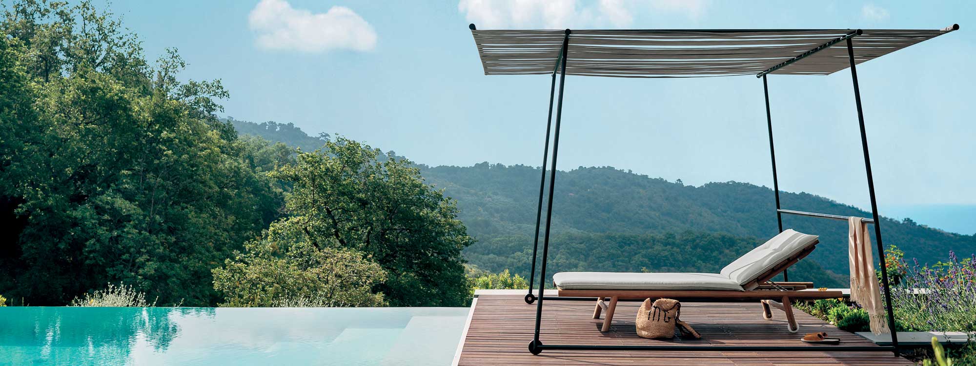 Image of RODA Ombrina minimalist pergola and Orson teak sun lounger, shown on horizon poolside with Italian hills and woodland in background