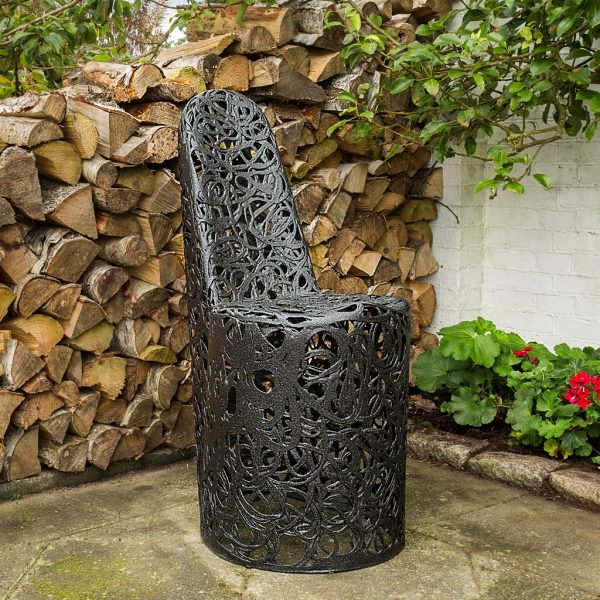 Image of Only black garden chair by Unknown Nordic against woodpile and geraniums in background