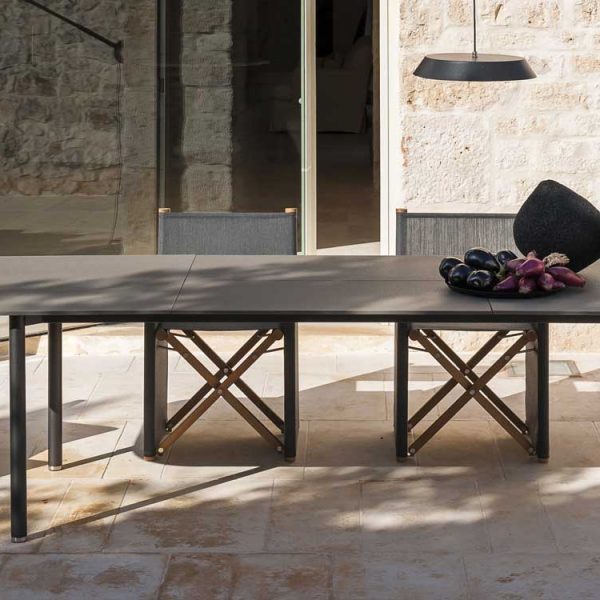 Image of RODA Piper extending ceramic garden table and grey & teak folding director chairs in sun and shade on rustic Italian terrace
