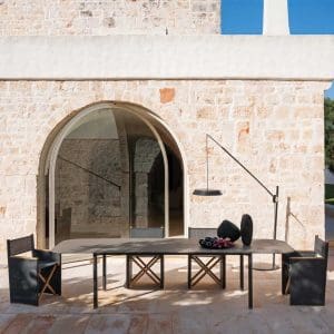 Image of opened RODA Piper extending garden table with Orson folding dining chairs in light and shade of rustic Italian courtyard
