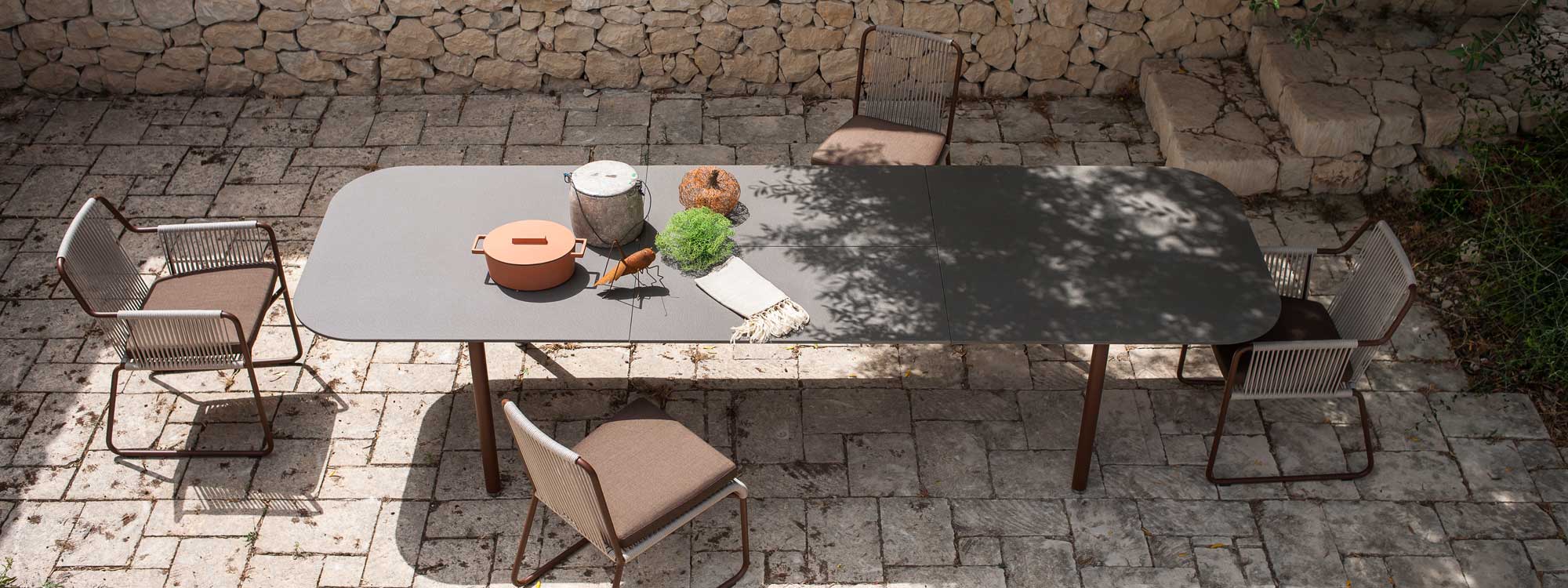 Image of aerial view of opened Piper extendable garden table and Harp dining chairs by RODA, shown in shady Italian courtyard