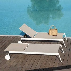 Image of pair of Piper white sun loungers with wheels by RODA, shown on wooden decked poolside
