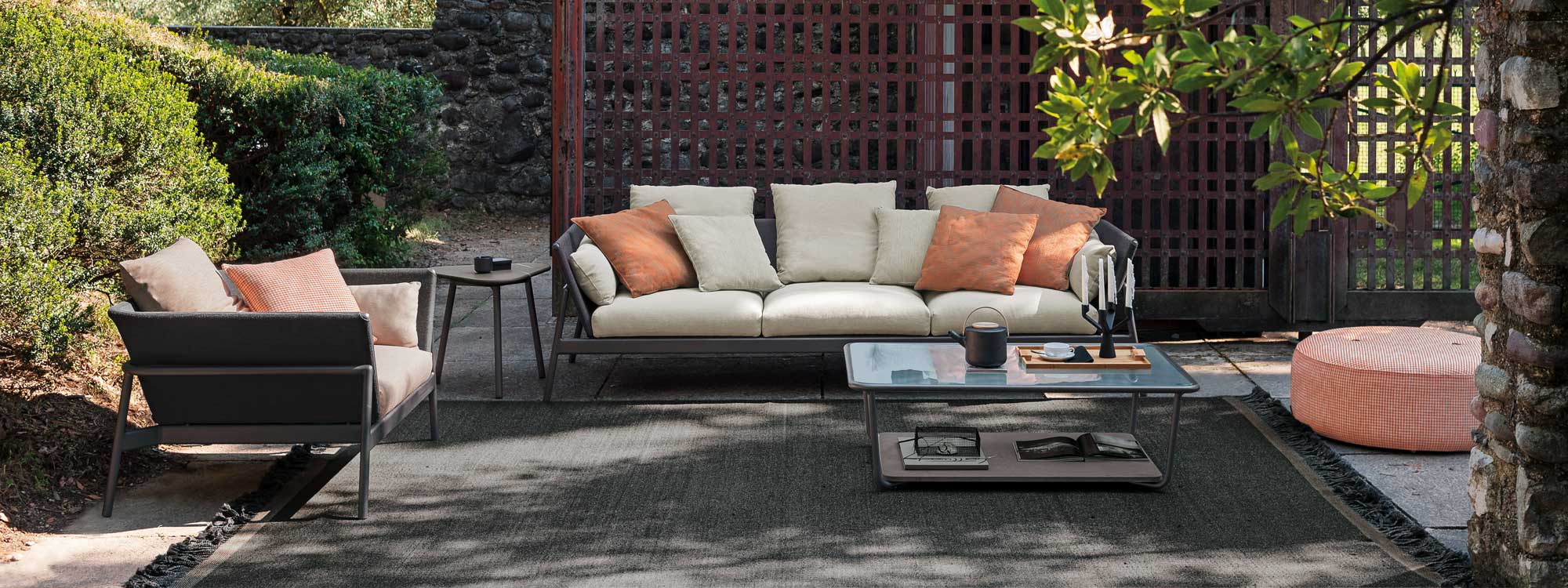 Image of RODA Piper garden sofa and lounge chair with Smoke-grey frame and cream and orange cushions
