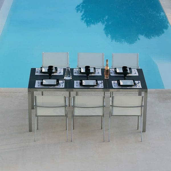 Image of black Taboela dining table and white QT 55 chairs by Royal Botania on terrace in front of swimming pool