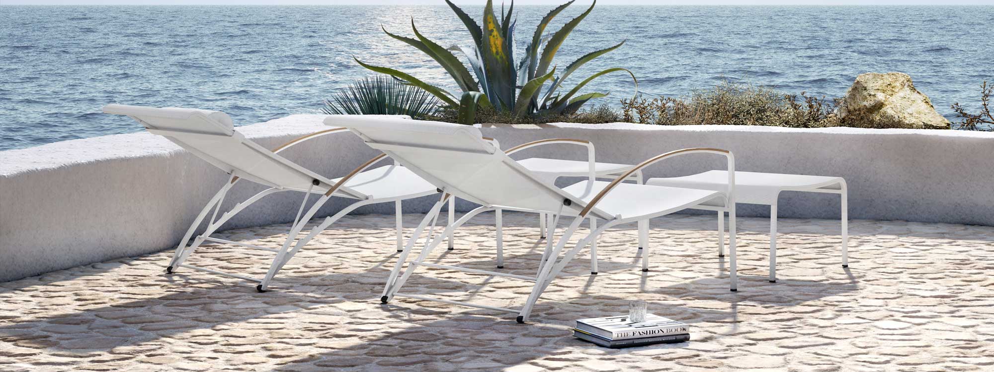Image of pair of white Royal Botania QT195 recliners on terrace with agaves and sea in background