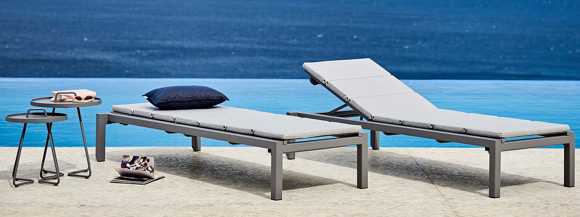 Image of pair of light-grey Relax sun loungers with light-grey cushions by Cane-line, shown on poolside