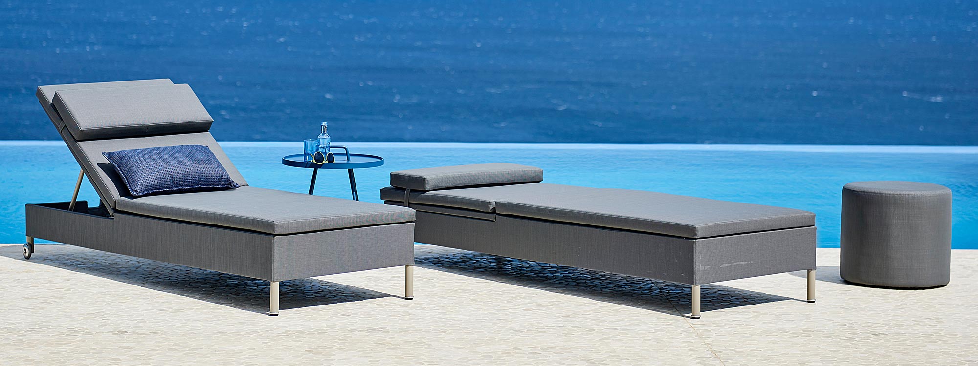 Image of pair of Caneline Rest grey sun loungers on poolside with sea in background