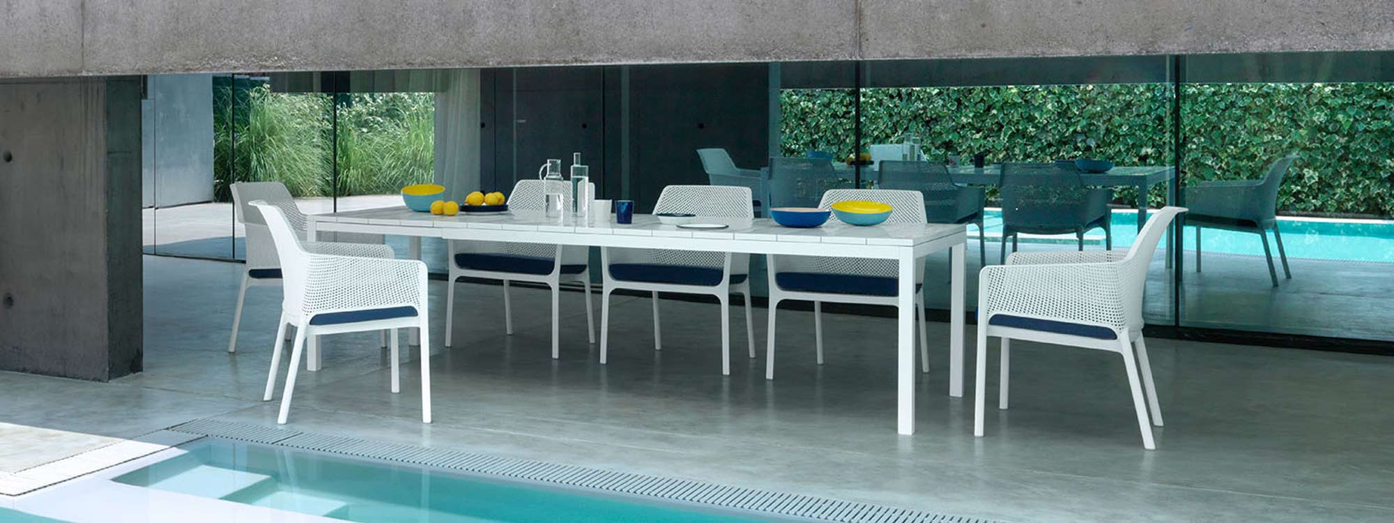 Image of white next garden chairs and white Rio extending garden table by Nardi, shown on minimalist poolside