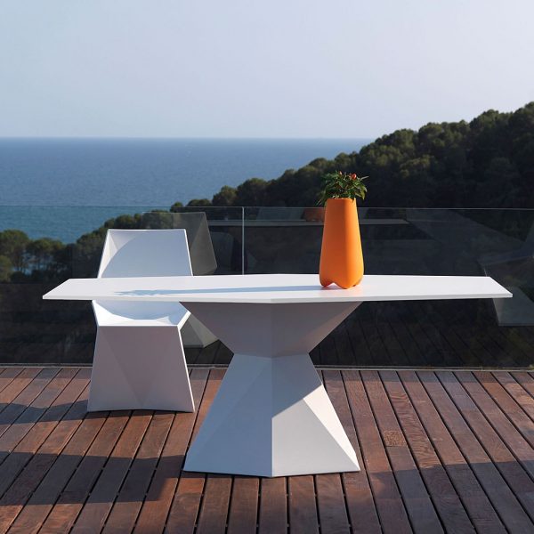 Image of Vondom Vertex modern white garden dining set on terrace with hills, sea and sky in the background