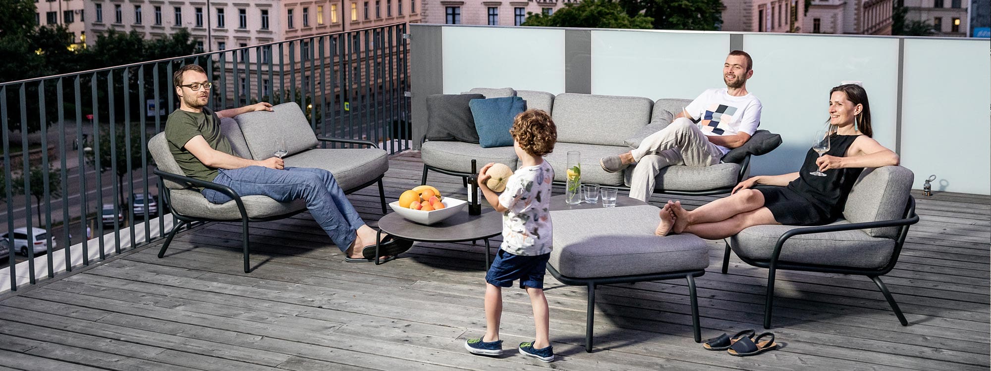 Image of 3 adults and a child relaxing on Todus Starling modern garden sofas on city rooftop terrace