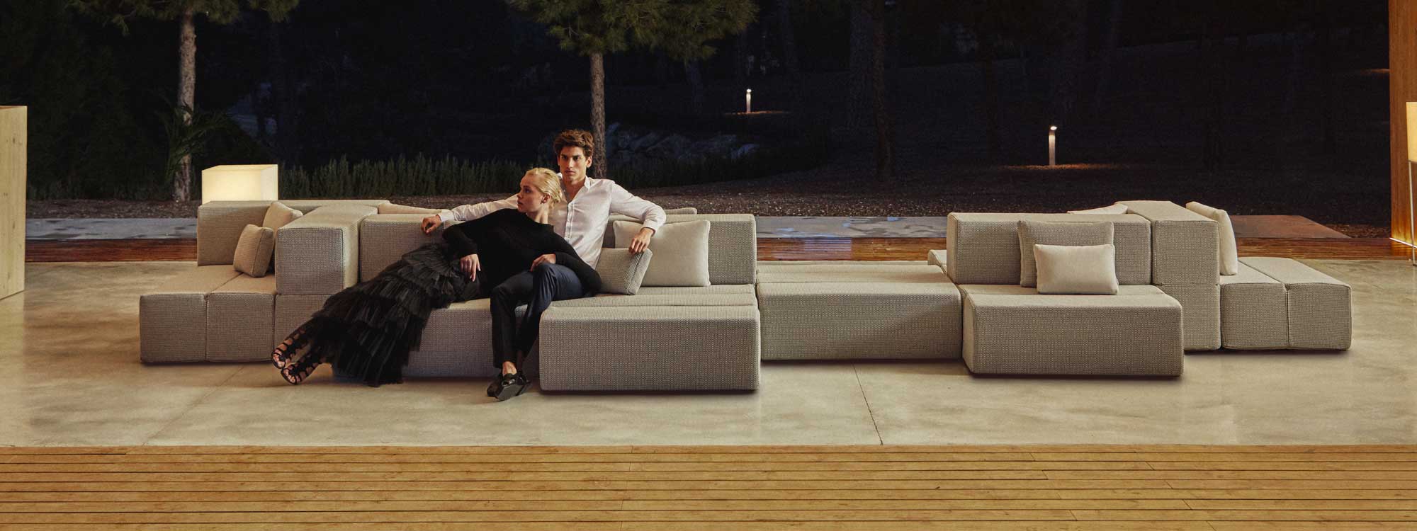 Nighttime shot of couple sat together on Vondom Tablet contemporary garden sofa
