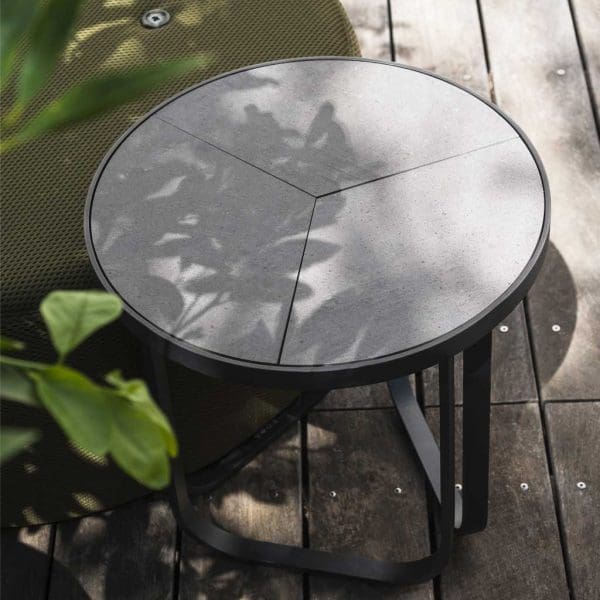 Image of RODA Thea round outdoor side table with sectional ceramic top, shown surrounded with plants in light and shade