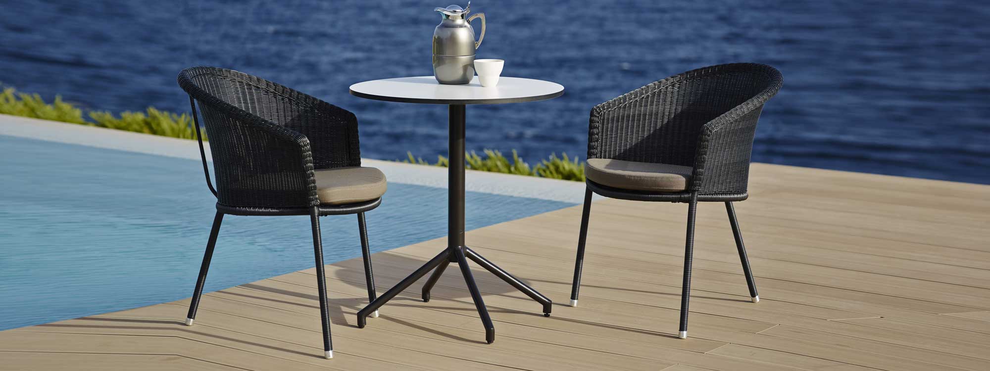 Image of Trinity stacking garden dining chairs by Caneline on wooden decked poolside
