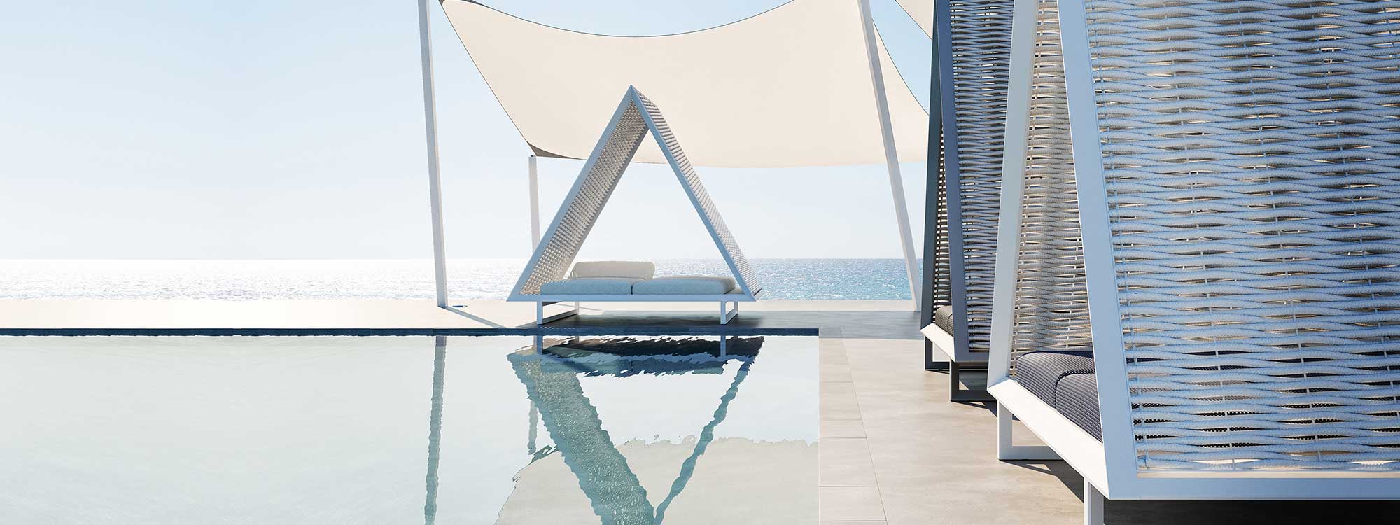 Image of Vondom Vineyard triangular outdoor daybeds around horizon pool beneath billowing canopies, with blue sea and sky in the background