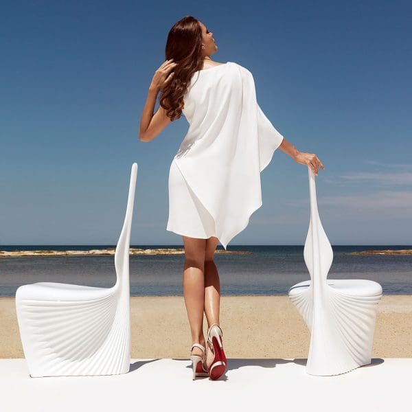 Image of woman stood between two Vondom Biophilia modernist garden chairs with beach and sea in the background