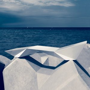 Image of Vondom Faz minimalist sunbed shown placed on tessellating coastal defense blocks with sea and sky in the background