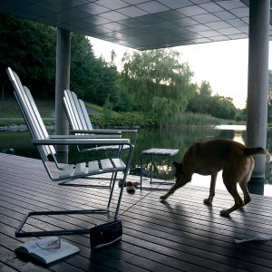 Image of A3 outdoor lounge chair and foot stool in White lacquered oak and galvanised steel on decking next to tranquil Swedish lake.