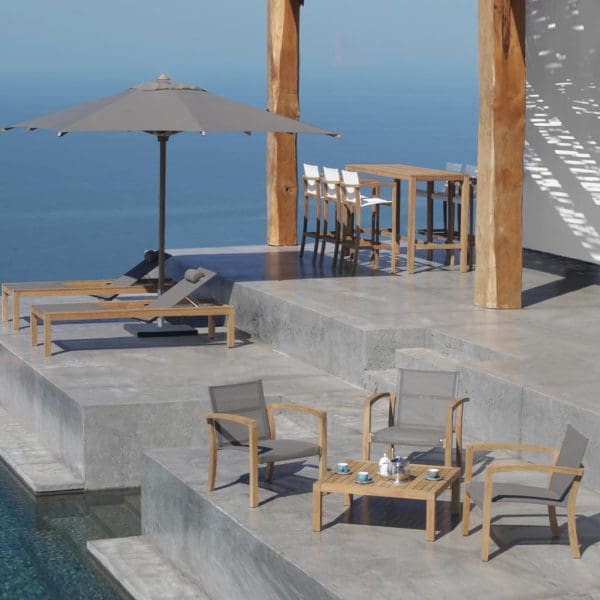Image of XQI teak lounge chairs and low table on terrace high above shimmering sea in background