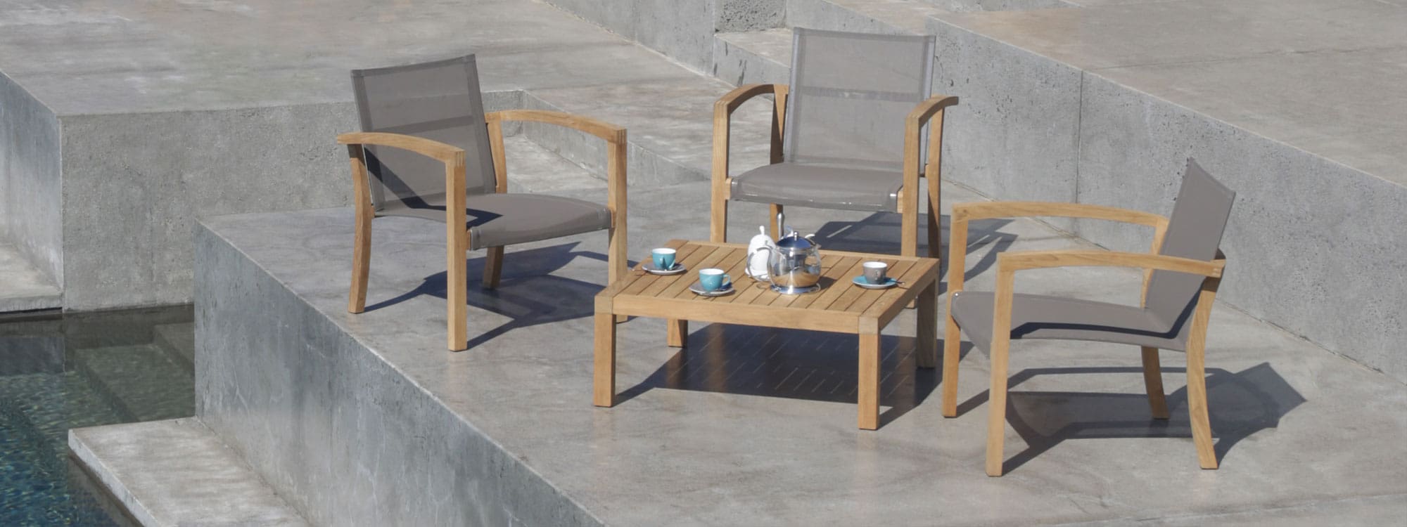 Image of XQI luxury teak garden lounge furniture by Royal Botania on poured concrete poolside