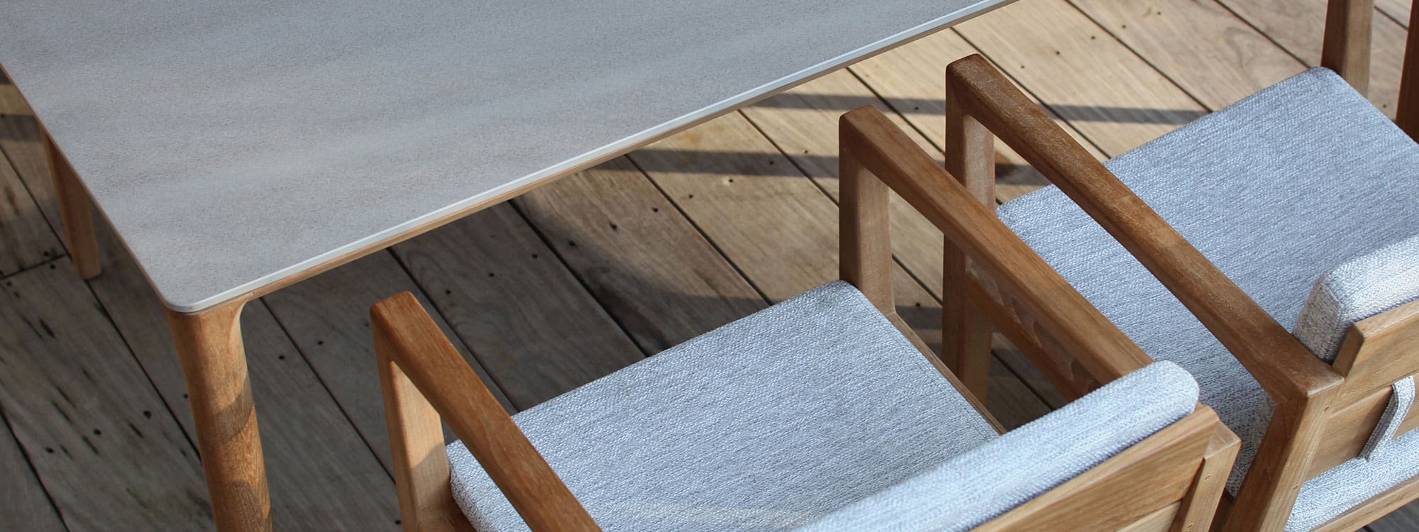 Image of detail of Zenhit teak chair's grey cushions and U-NITE table's ceramic table top by Royal Botania