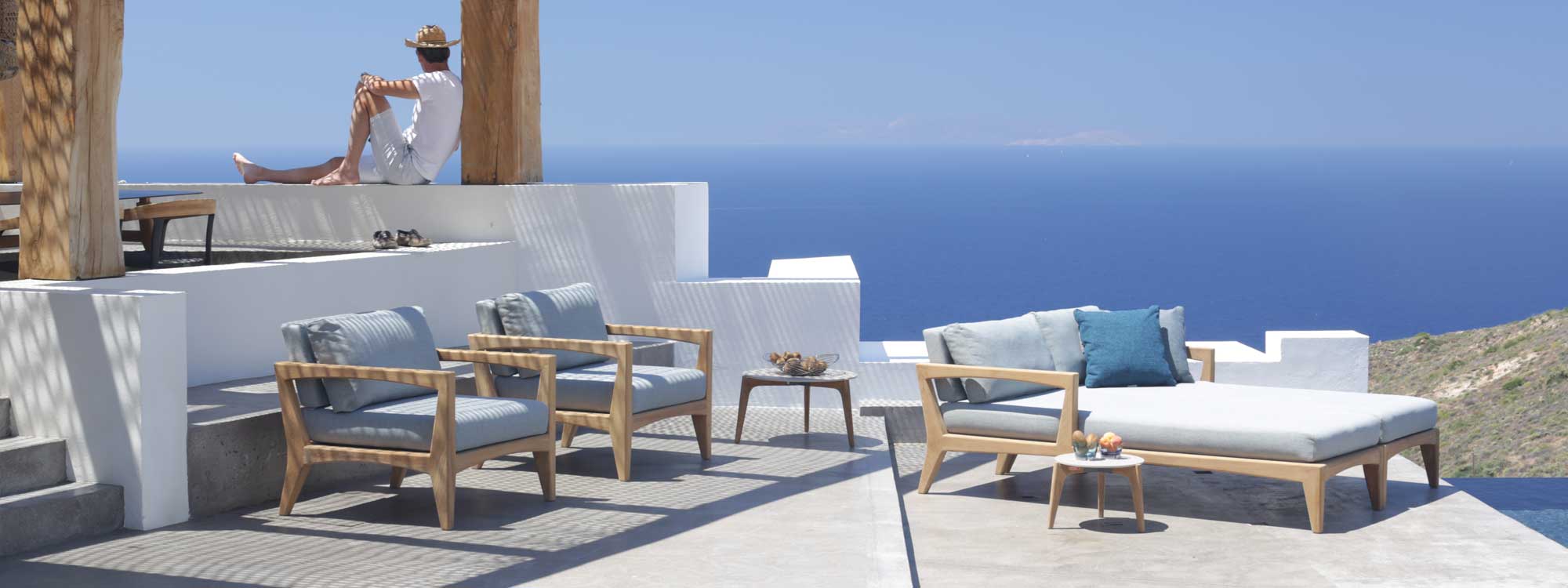 Image of Royal Botania Zenhit teak lounge chairs and daybeds on Greek island terrace overlooking the Mediterranean.