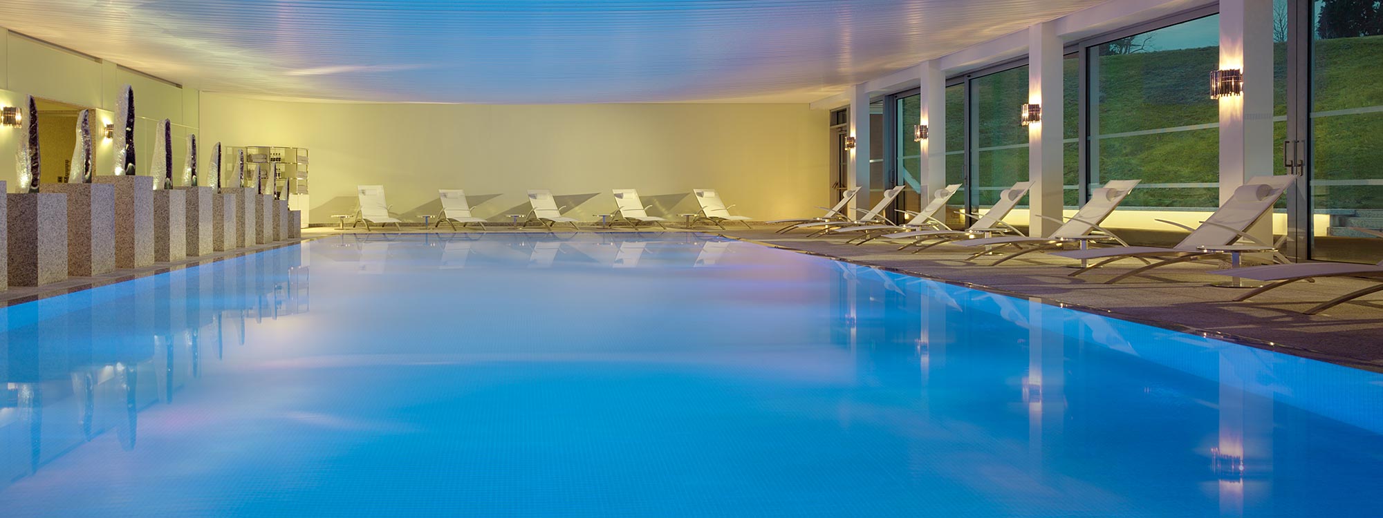 Image of Royal Botania OZON sun loungers around the indoor swimming pool at Coworth Park luxury spa