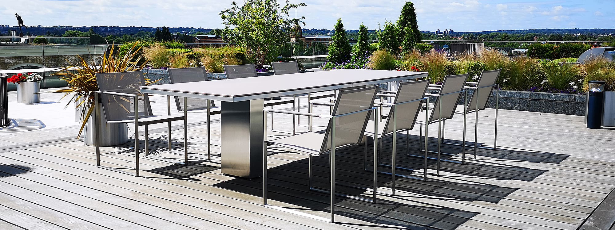 Image of Doble modern garden table and Butaque chairs in brushed stainless steel on London roof top terrace by FueraDentro