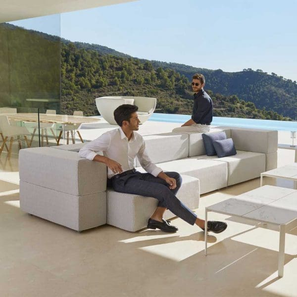 Image of couple of men sat on chunky Tablet garden sofa by Vondom on sunny Spanish terrace with swimming pool and hillside in the background
