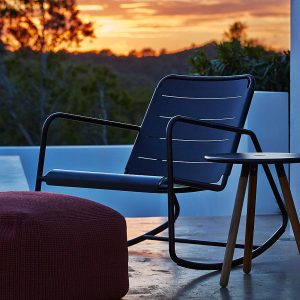 Image of Copenhagen outdoor rocking chair by Caneline shown on terrace at dusk