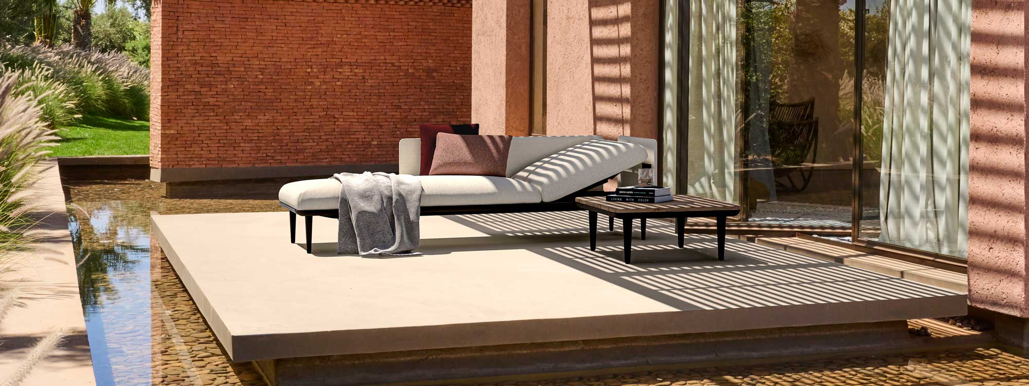 Image of Styletto upholstered garden lounger by Royal Botania pictured on terrace surrounded by water feature