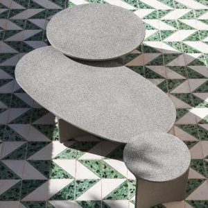 Image of 3 different sizes of circular and oval Aspic concrete outdoor tables by RODA, on green and white tessellating floor tiles