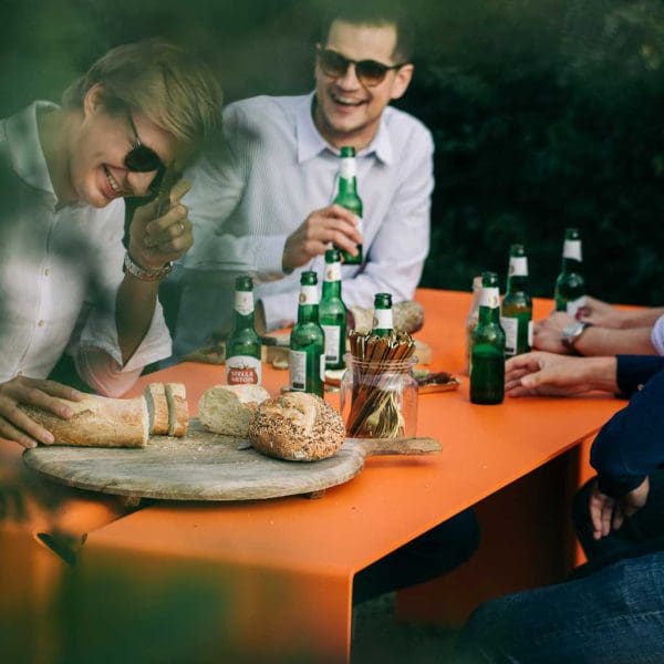 Image of friends enjoying a beer and food whilst sat at The Bended modern garden table and benches by Wunder, Belgium