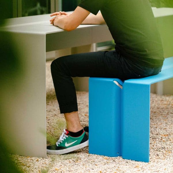 Image of man sat on The Bended blue garden bench whilst resting his elbows on The Bended light-grey garden table by Wunder