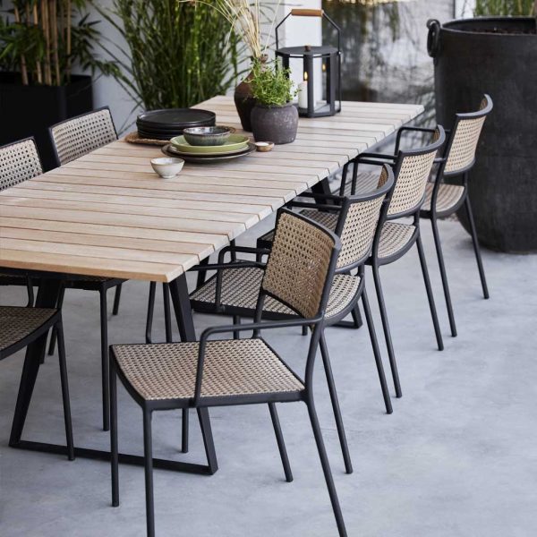 Image of Less garden chairs in natural Cane-line French weave with lava-grey frames, next to Copenhagen extendable teak dining table with lava-grey legs