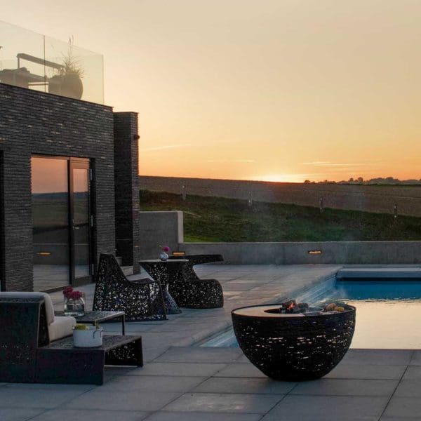 Image of smoking Lava Nest bbq & Lava Lounge furniture by Unknown Nordic on poolside at dusk