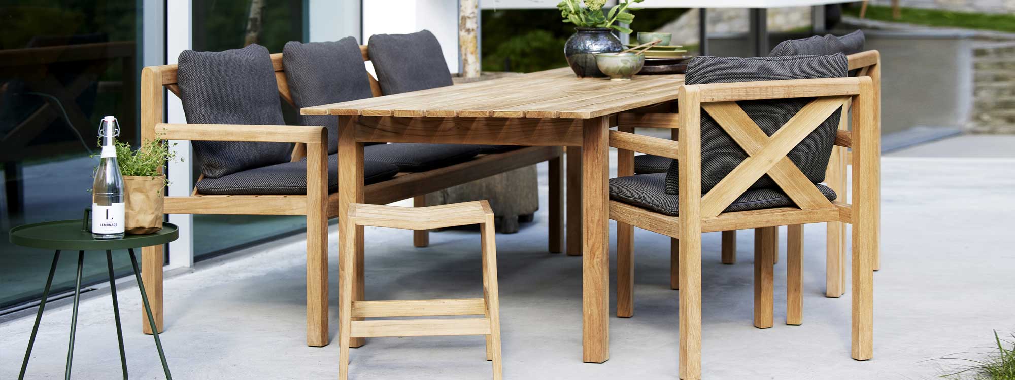 Image of Flip teak stool and Grace teak table, bench and chairs by Cane-line garden furniture