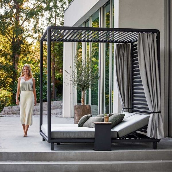 Image of walking next to Laze adjustable garden daybed with curtains by Cane-line