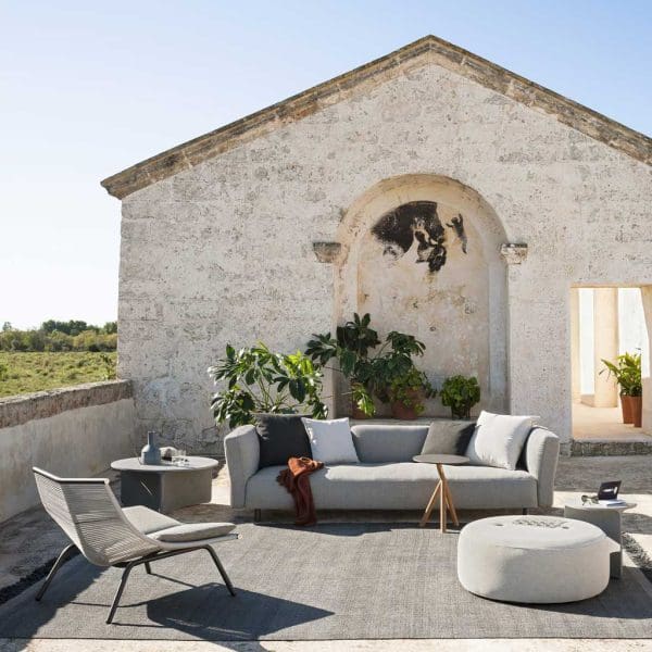 Image of RODA Mamba garden sofa and Laze modern relax chairs on carpet, with rustic building in background