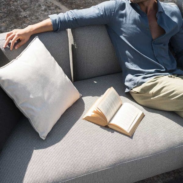 Image of man sitting in RODA Mamba garden sofa with his arm resting on the back cushions