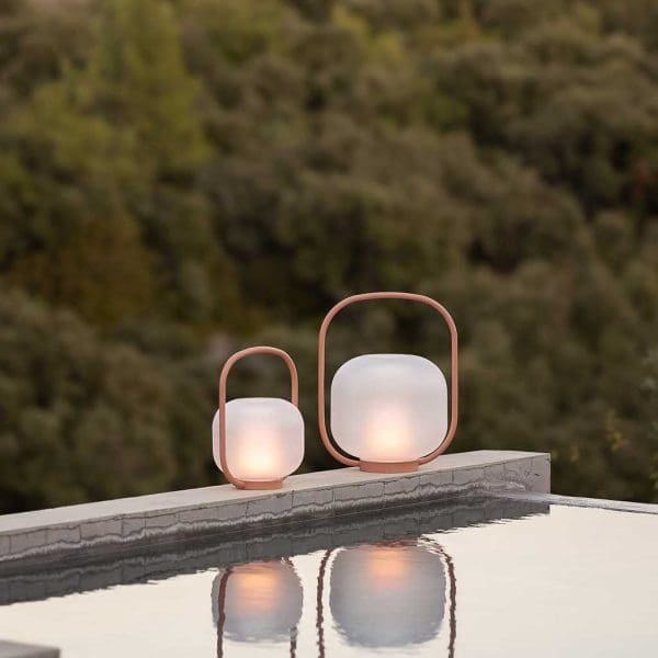 Image of pair of Todus Otus outdoor LED lanterns on poolside with their reflection shown in the water below